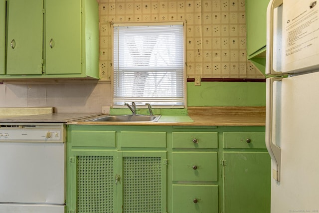 kitchen with green cabinetry, white appliances, light countertops, and a sink