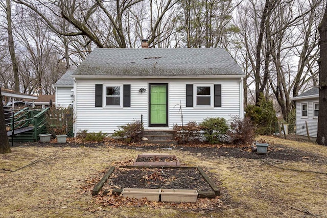 view of front of home featuring a garden, a chimney, and a shingled roof