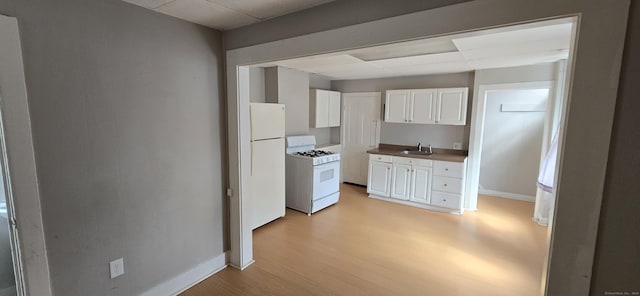 kitchen with white cabinetry, white appliances, light wood-style floors, and a sink