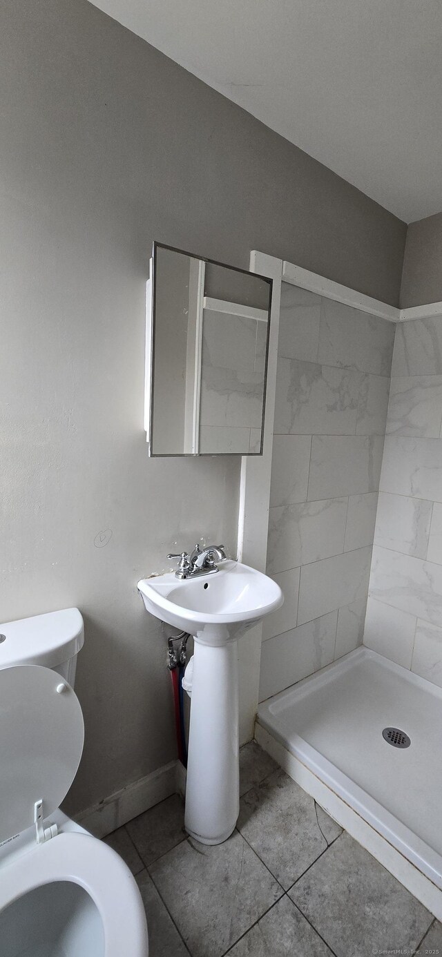 bathroom with tile patterned flooring, a shower stall, toilet, and baseboards