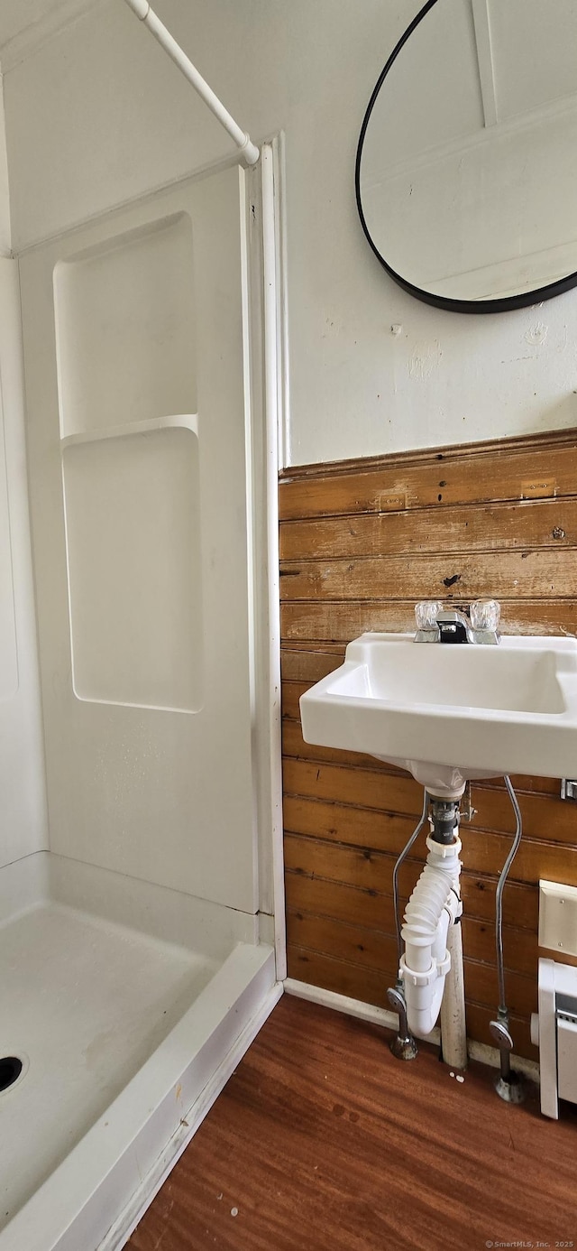 full bathroom with a sink, a shower stall, and wood finished floors
