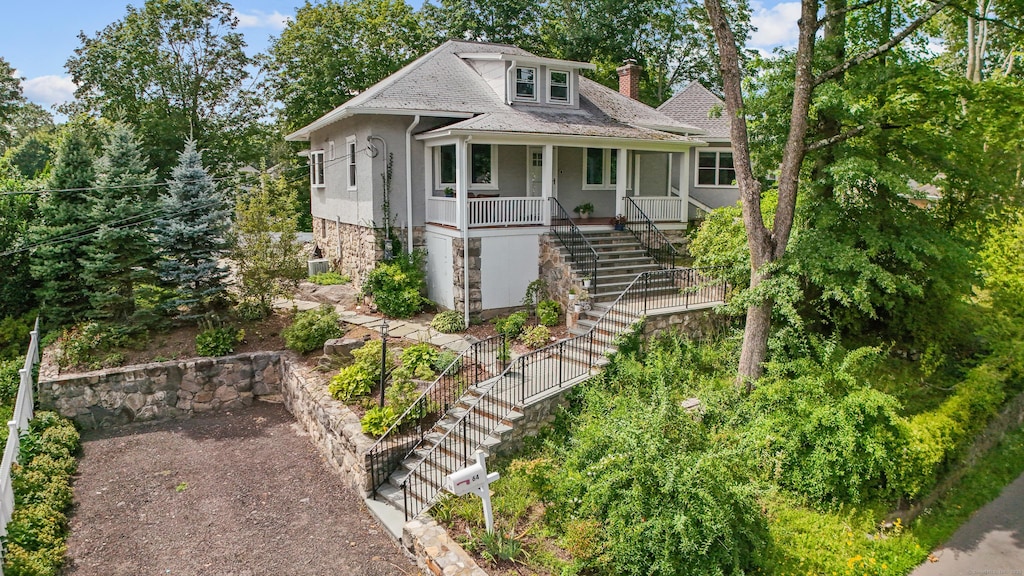 view of front facade featuring stairway, covered porch, and a chimney