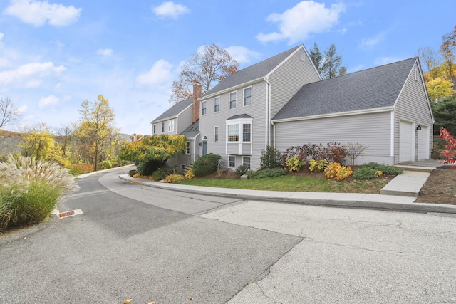 view of front of house with an attached garage, driveway, and roof with shingles