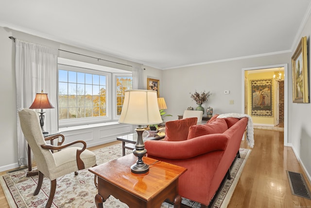 living room featuring visible vents, a notable chandelier, ornamental molding, wood finished floors, and baseboards