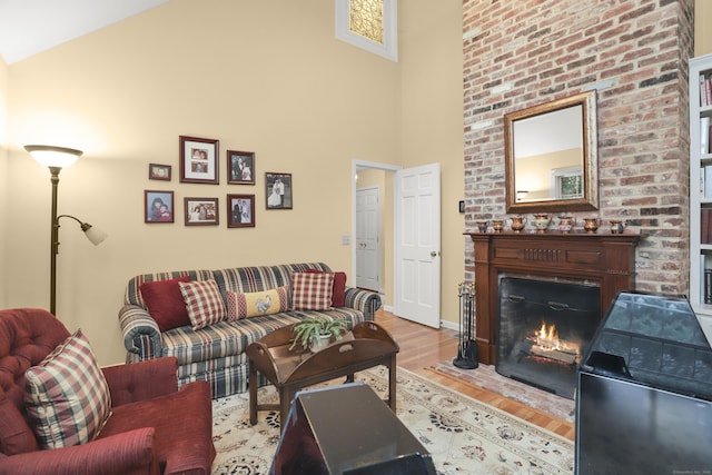 living area with baseboards, a high ceiling, a warm lit fireplace, and wood finished floors