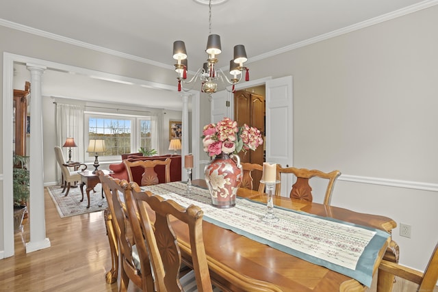 dining area featuring crown molding, baseboards, decorative columns, light wood-style flooring, and an inviting chandelier