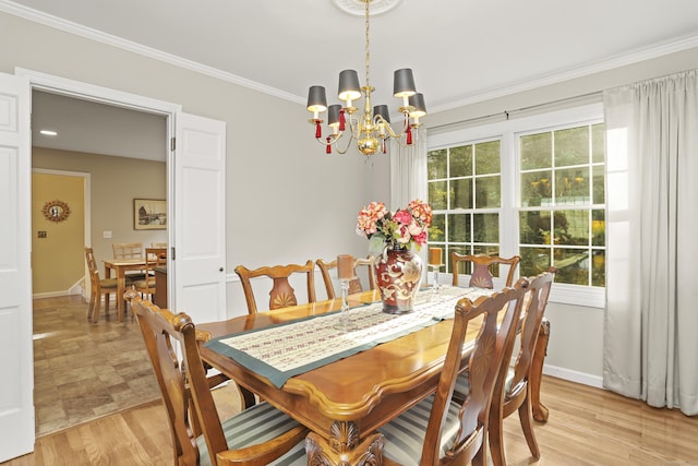 dining room with a chandelier, baseboards, ornamental molding, and light wood finished floors