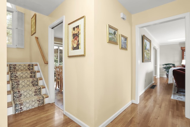 hallway featuring visible vents, stairs, baseboards, and wood finished floors