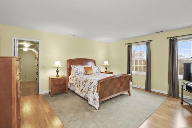 bedroom with visible vents, multiple windows, and wood finished floors