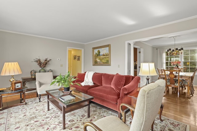 living area with decorative columns, wood finished floors, a chandelier, and ornamental molding