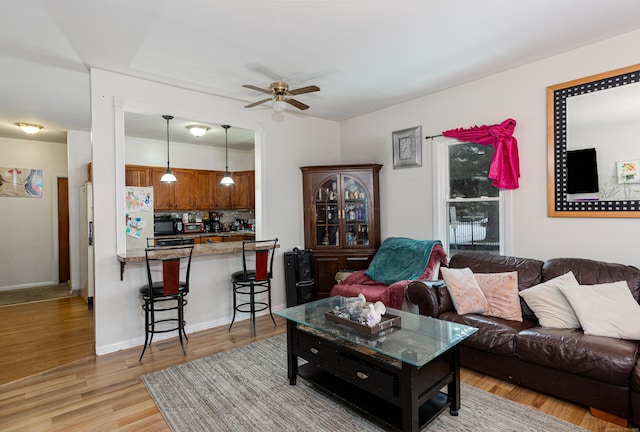 living room featuring light wood-type flooring, baseboards, and a ceiling fan