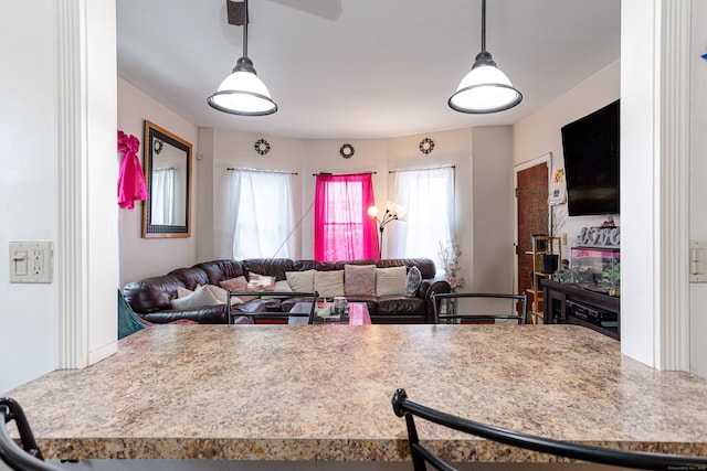 kitchen with light countertops, a ceiling fan, open floor plan, and pendant lighting