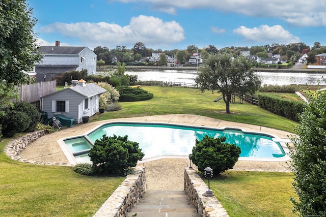 view of swimming pool with a lawn, a pool with connected hot tub, fence, and a water view