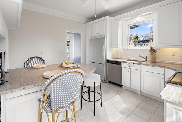 kitchen with a sink, decorative backsplash, white cabinets, appliances with stainless steel finishes, and crown molding