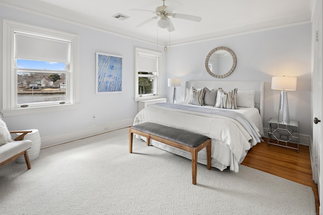 bedroom featuring crown molding, wood finished floors, visible vents, and baseboards