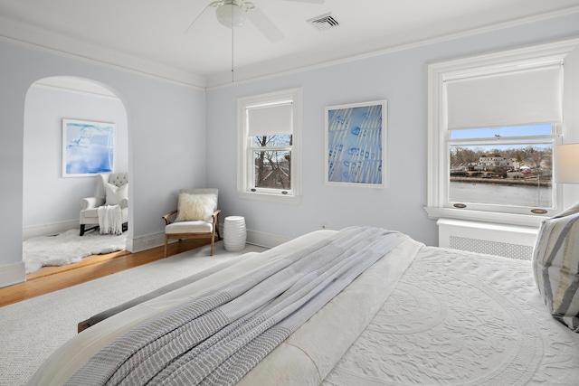 bedroom with wood finished floors, visible vents, baseboards, arched walkways, and ceiling fan