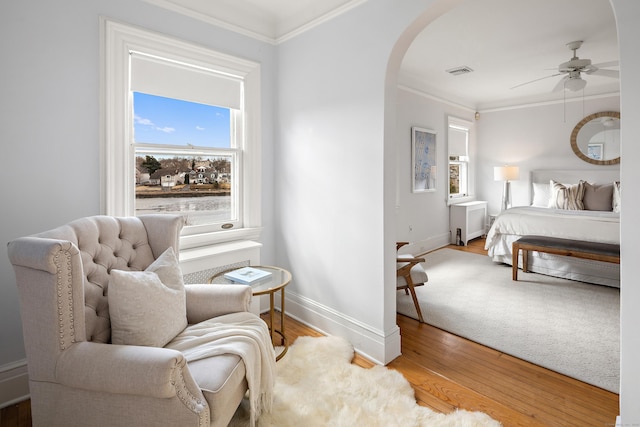 bedroom with visible vents, arched walkways, wood finished floors, and crown molding