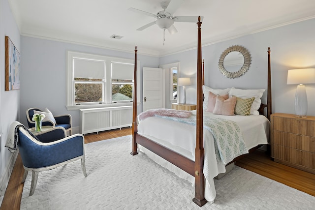 bedroom with radiator, wood finished floors, visible vents, and ornamental molding