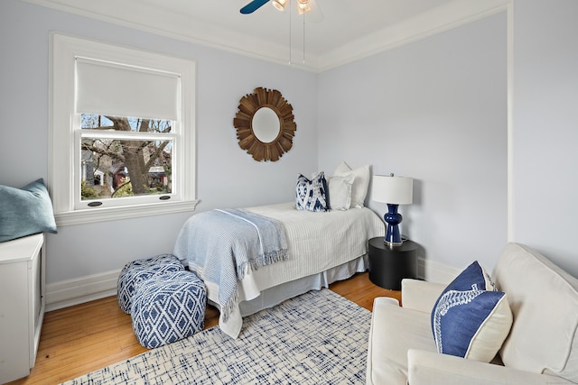 bedroom featuring ceiling fan, crown molding, baseboards, and wood finished floors