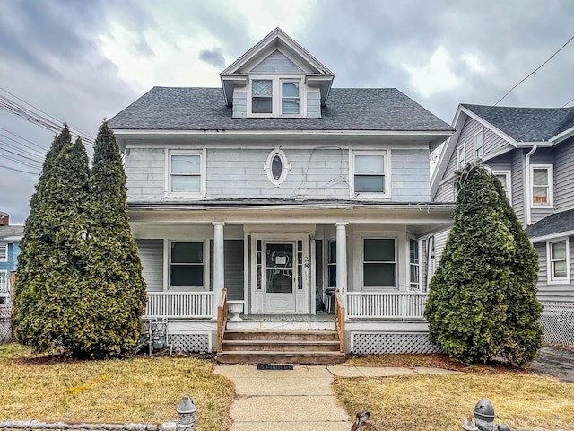 traditional style home with covered porch and roof with shingles