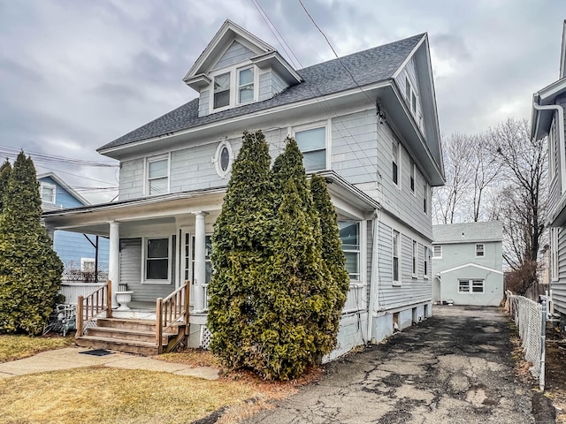 traditional style home with covered porch, driveway, and a shingled roof