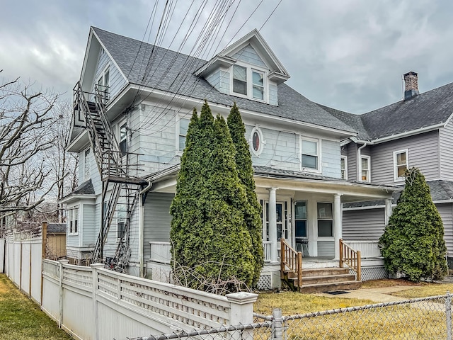 american foursquare style home featuring stairs, a porch, a fenced front yard, and roof with shingles