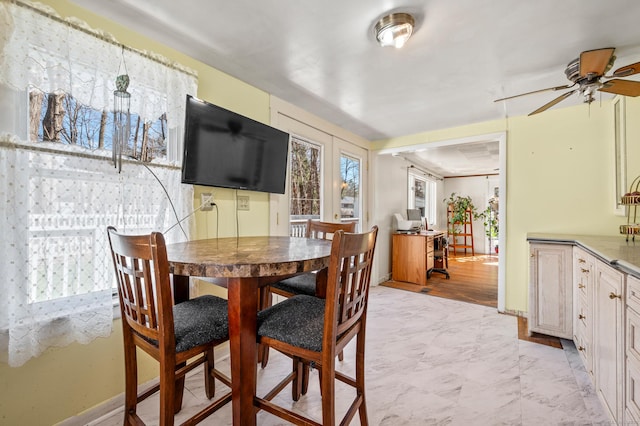 dining space featuring baseboards, marble finish floor, and ceiling fan