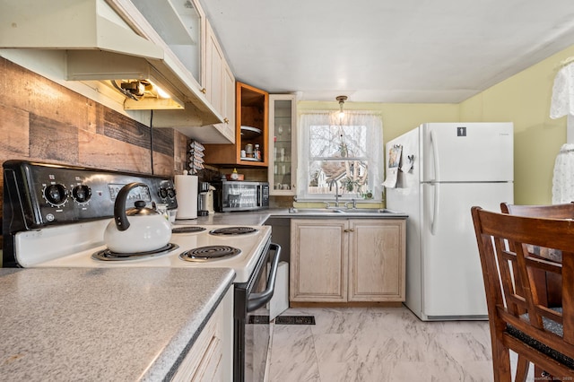 kitchen with freestanding refrigerator, a sink, electric range oven, glass insert cabinets, and stainless steel microwave