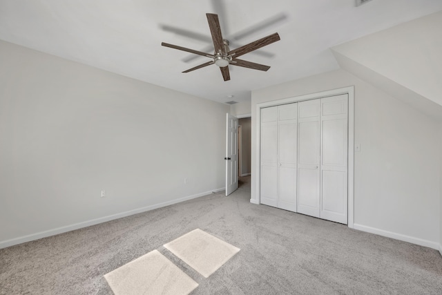 unfurnished bedroom featuring a closet, carpet floors, baseboards, ceiling fan, and vaulted ceiling