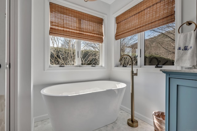 bathroom with a soaking tub, baseboards, and a wealth of natural light