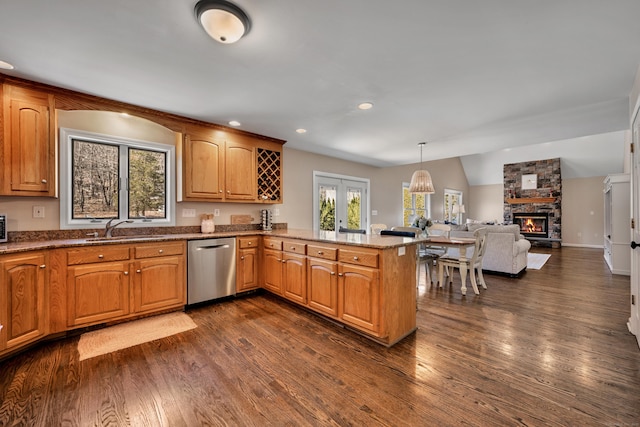 kitchen featuring a sink, stainless steel dishwasher, a peninsula, and a wealth of natural light