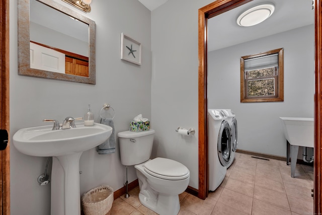 half bath featuring washing machine and clothes dryer, tile patterned flooring, toilet, and baseboards