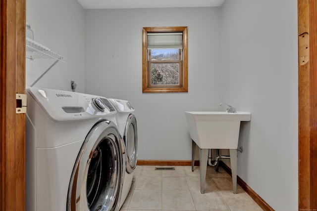 washroom featuring visible vents, separate washer and dryer, light tile patterned floors, baseboards, and laundry area