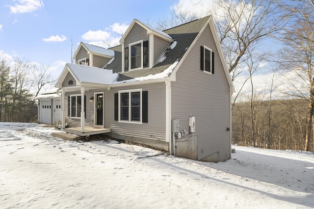 cape cod house featuring an attached garage and a shingled roof