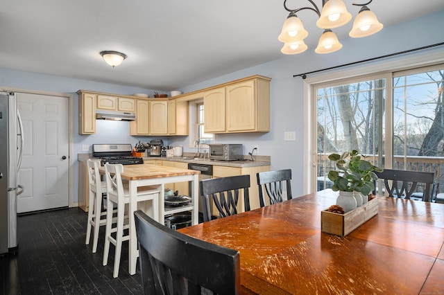 kitchen with under cabinet range hood, light brown cabinetry, appliances with stainless steel finishes, wood counters, and a sink