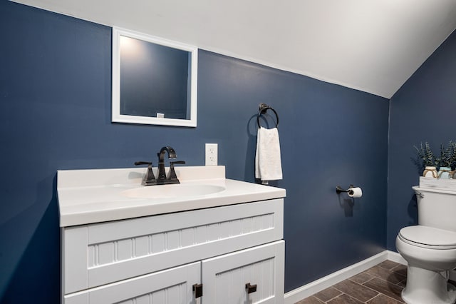 bathroom with baseboards, wood tiled floor, toilet, lofted ceiling, and vanity