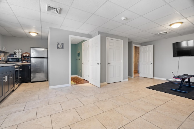 exercise room featuring light tile patterned floors, visible vents, baseboards, and a drop ceiling