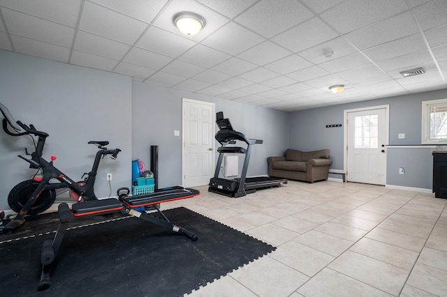 workout area with light tile patterned flooring, visible vents, a paneled ceiling, and baseboards