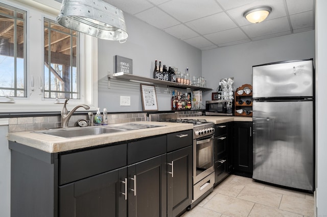 kitchen with light tile patterned floors, open shelves, a drop ceiling, a sink, and appliances with stainless steel finishes