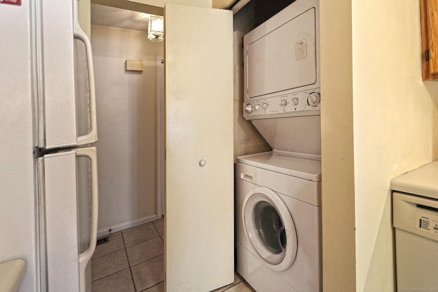 laundry room featuring baseboards, stacked washer and clothes dryer, light tile patterned flooring, and laundry area