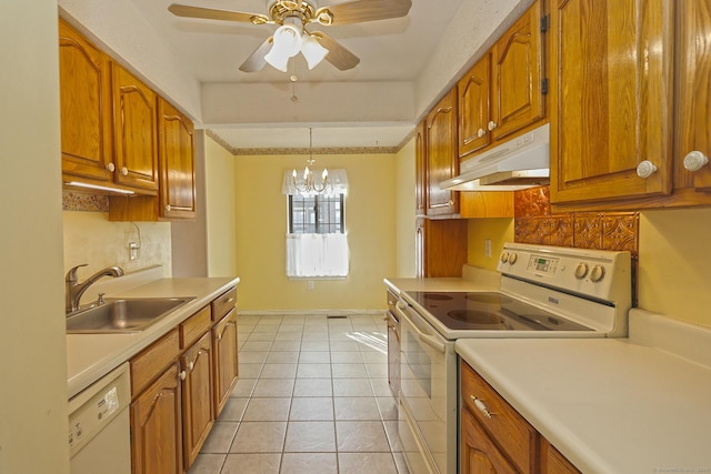 kitchen with under cabinet range hood, decorative backsplash, brown cabinets, white appliances, and a sink