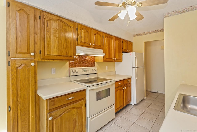 kitchen with white appliances, light tile patterned flooring, a sink, light countertops, and under cabinet range hood