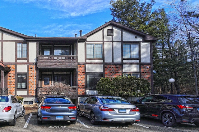 view of front of property featuring stucco siding, brick siding, and uncovered parking