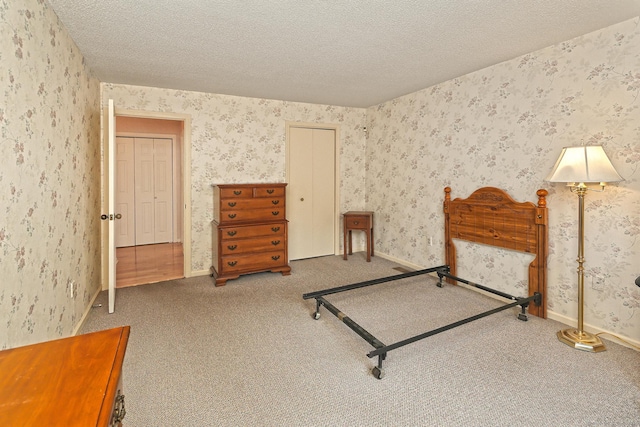 bedroom with a textured ceiling, wallpapered walls, and carpet