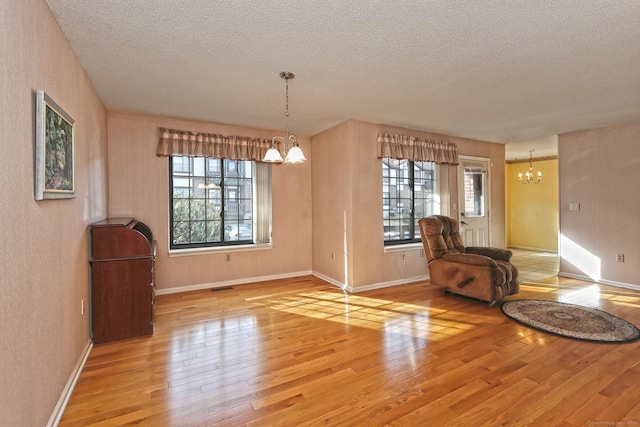 unfurnished room featuring a healthy amount of sunlight, an inviting chandelier, and hardwood / wood-style flooring