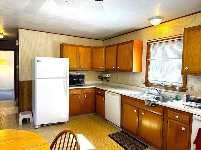 kitchen with wallpapered walls, white appliances, light floors, and a sink