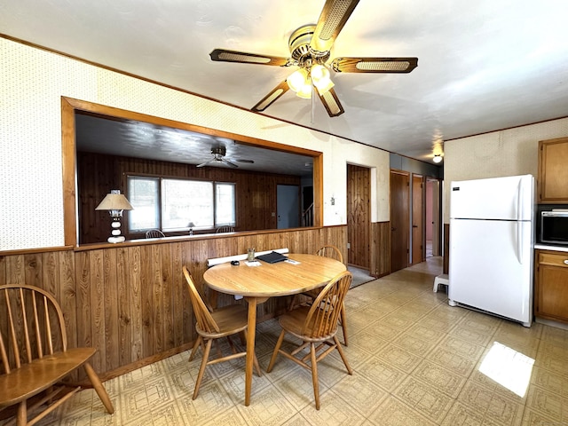 dining area with wainscoting, wallpapered walls, and light floors