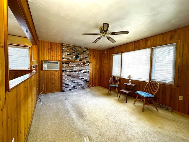 sitting room featuring wooden walls, carpet flooring, a wall mounted air conditioner, and ceiling fan