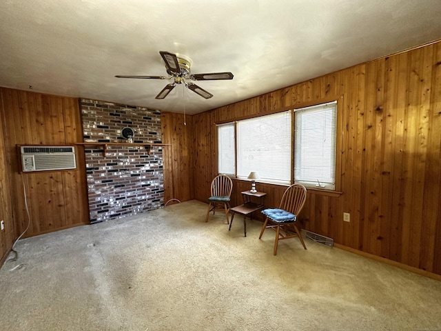 sitting room featuring wooden walls, a wall mounted air conditioner, a ceiling fan, and carpet floors