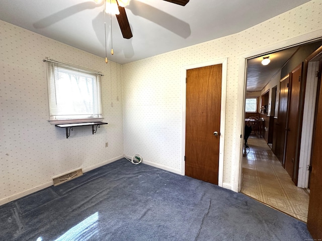 carpeted spare room featuring visible vents, baseboards, ceiling fan, and wallpapered walls